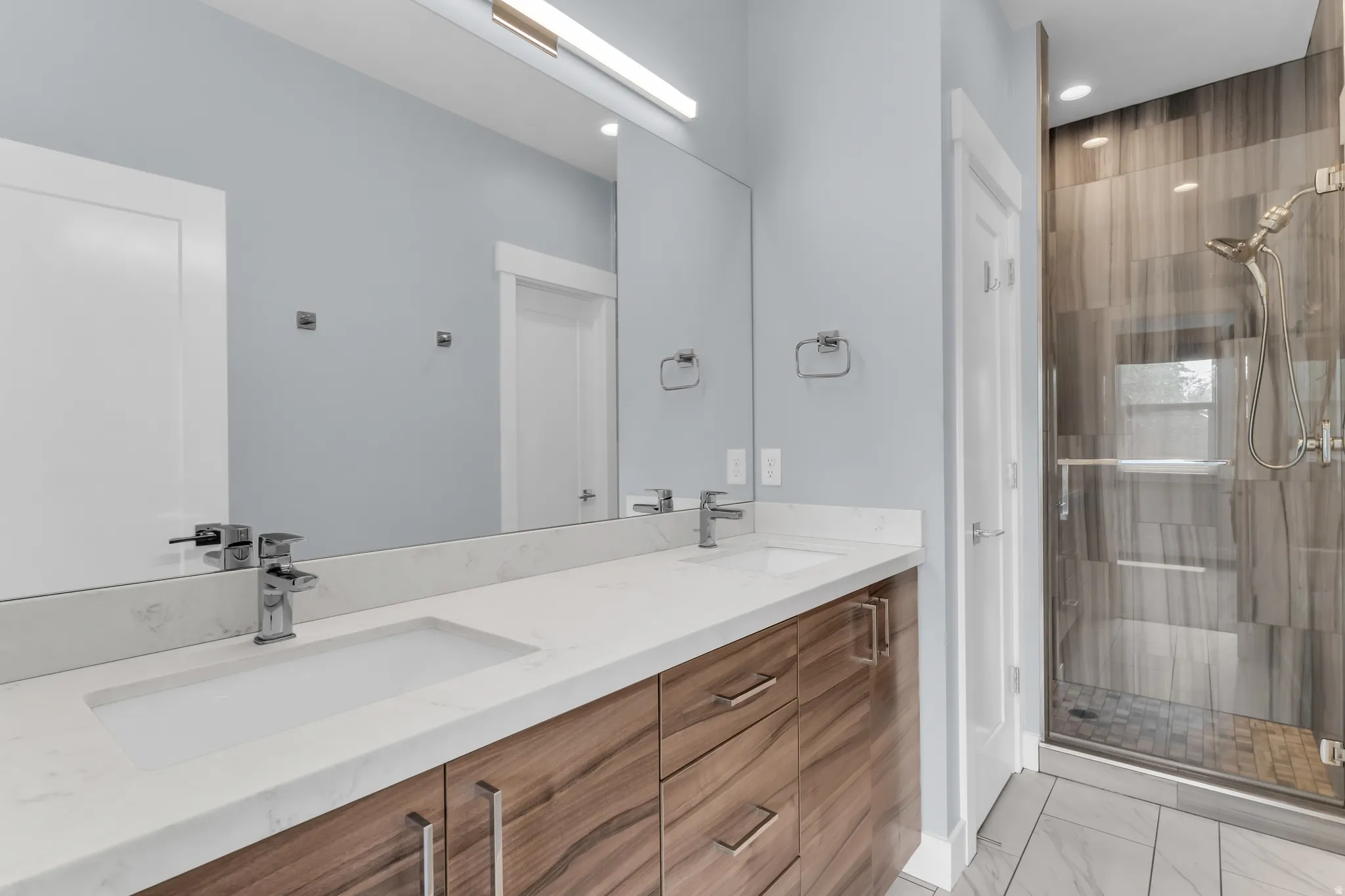 Primary bathroom. Dual vanity with wood-finish cabinetry, integrated rectangular sinks, and chrome fixtures