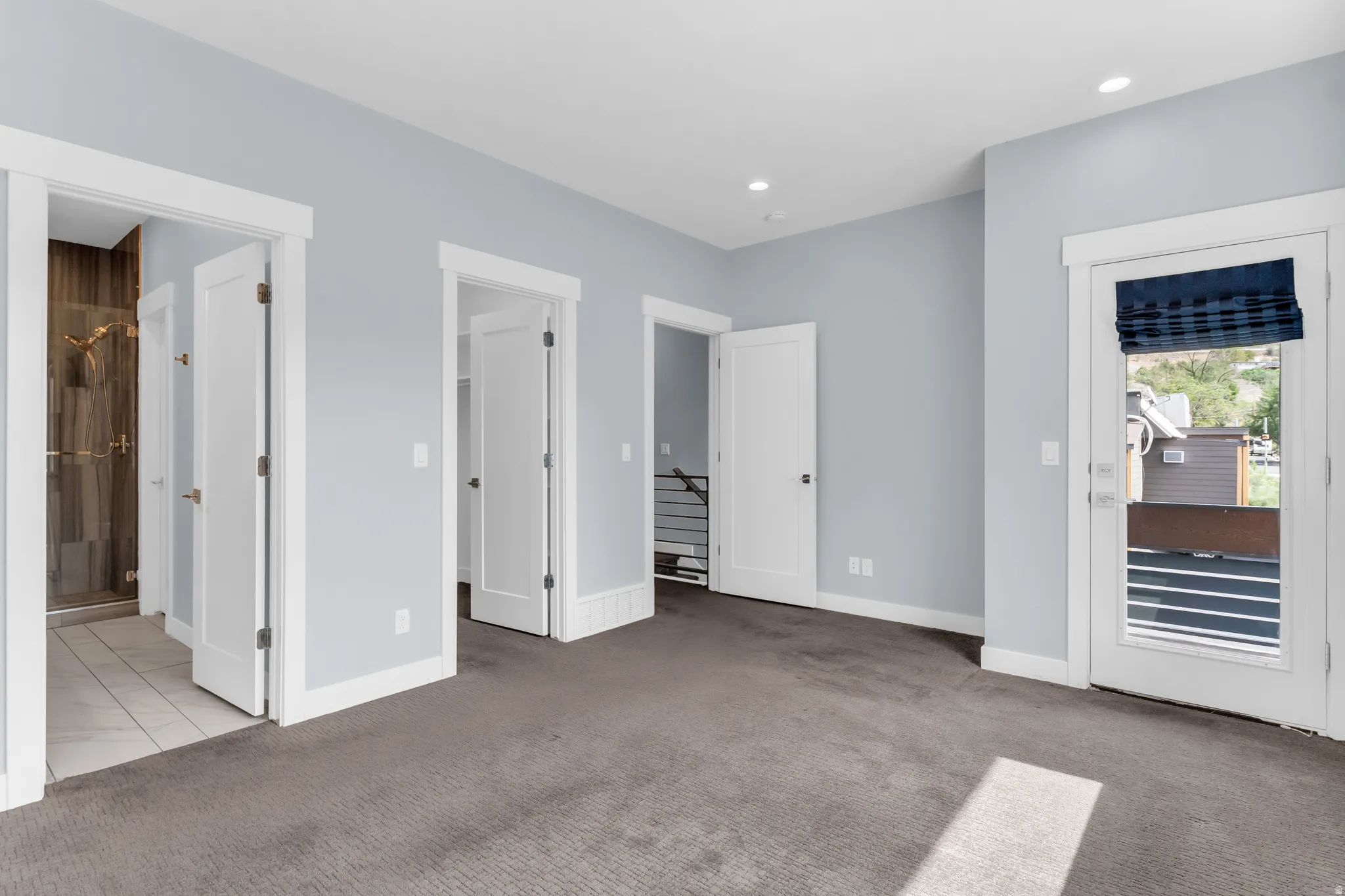 Carpeted flooring, recessed lighting, and a glass-enclosed shower with tile surround