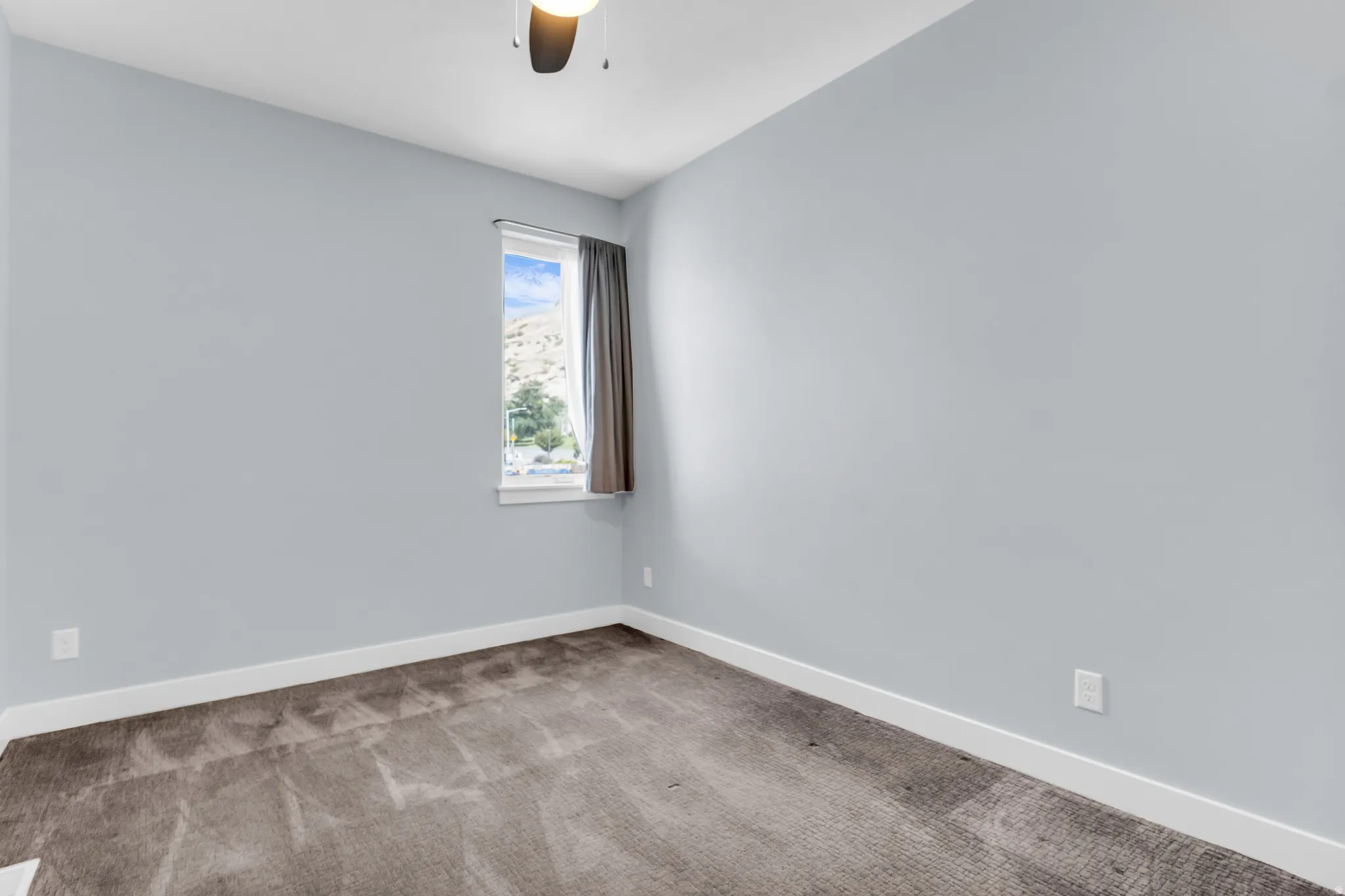 Recessed window with white trim, ceiling fan light fixture, light gray wall finish, and gray carpet flooring