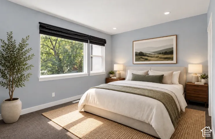 Recessed lighting, large windows with black privacy blinds, carpet flooring, and a light-colored headboard
