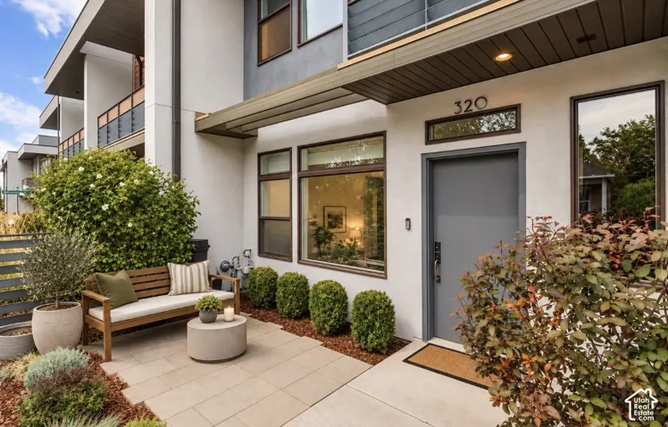 Entry patio with paver flooring, a gray privacy fence, a gray entry door, and dark-framed windows