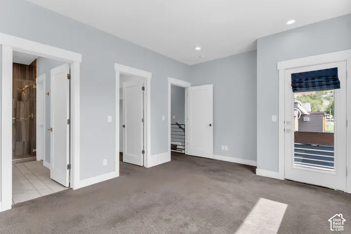 Carpeted flooring, recessed lighting, and a glass-enclosed shower with tile surround