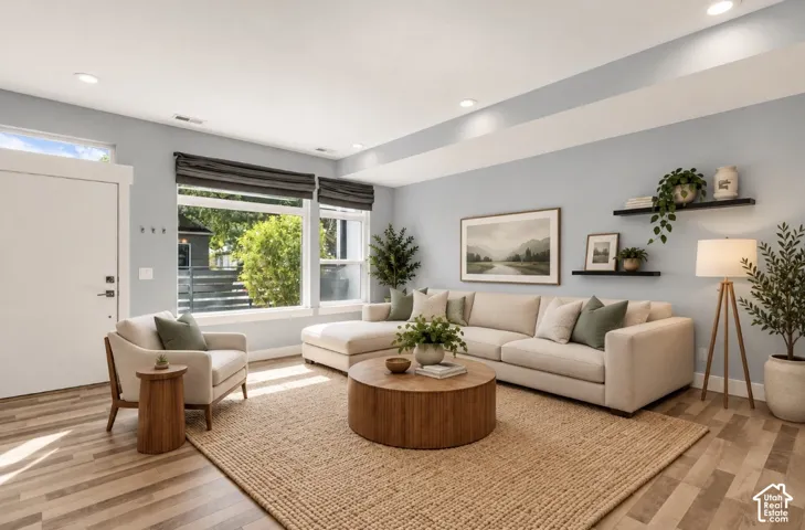 Large windows, recessed lighting, wood-finish flooring, a contemporary white door, and light blue wall paint