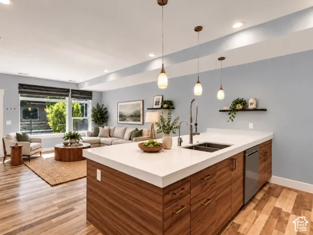 Open-concept living space featuring wood-finish flooring, a kitchen island with integrated stainless steel appliances, and large windows