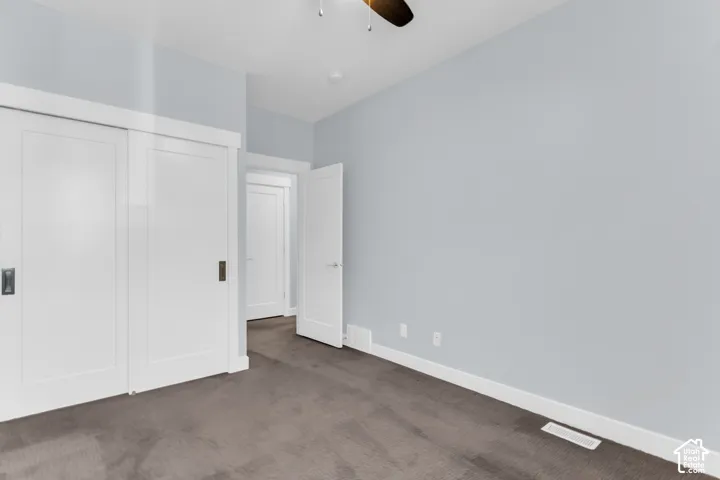Sliding panel closet doors with dark hardware, light gray wall finish, white trim, and a dark carpeted floor