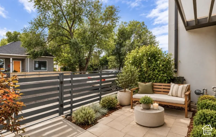 Paved patio with modern slatted fencing, mature landscaping, and an overhead pergola structure