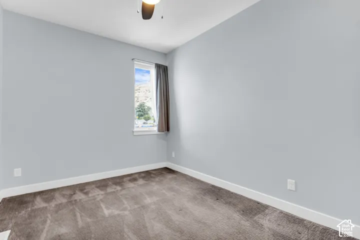 Recessed window with white trim, ceiling fan light fixture, light gray wall finish, and gray carpet flooring