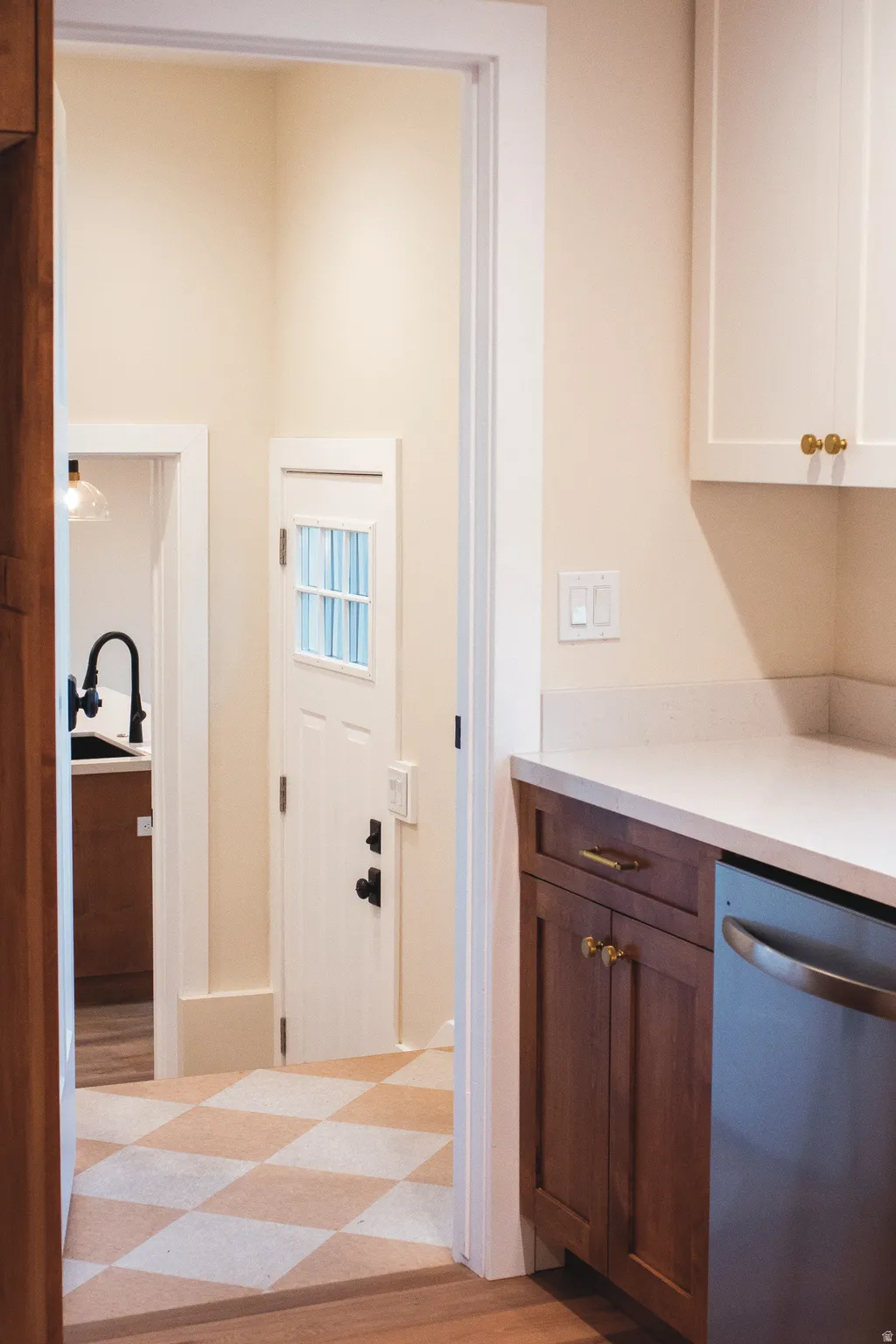 Kitchen area featuring white upper cabinetry, rich wood-finish lower cabinetry, light-toned countertop, and a stainless steel appliance