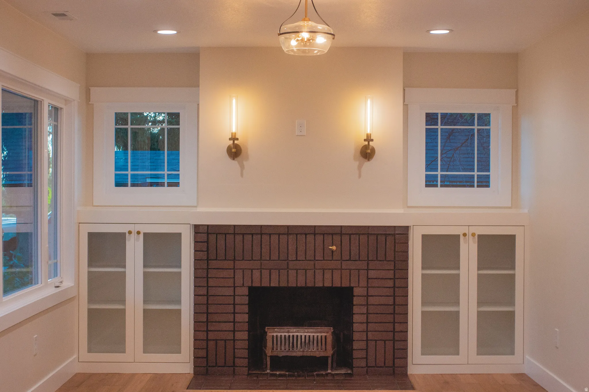 Brick-faced fireplace with a built-in firebox, flanked by custom cabinetry with glass-paneled doors