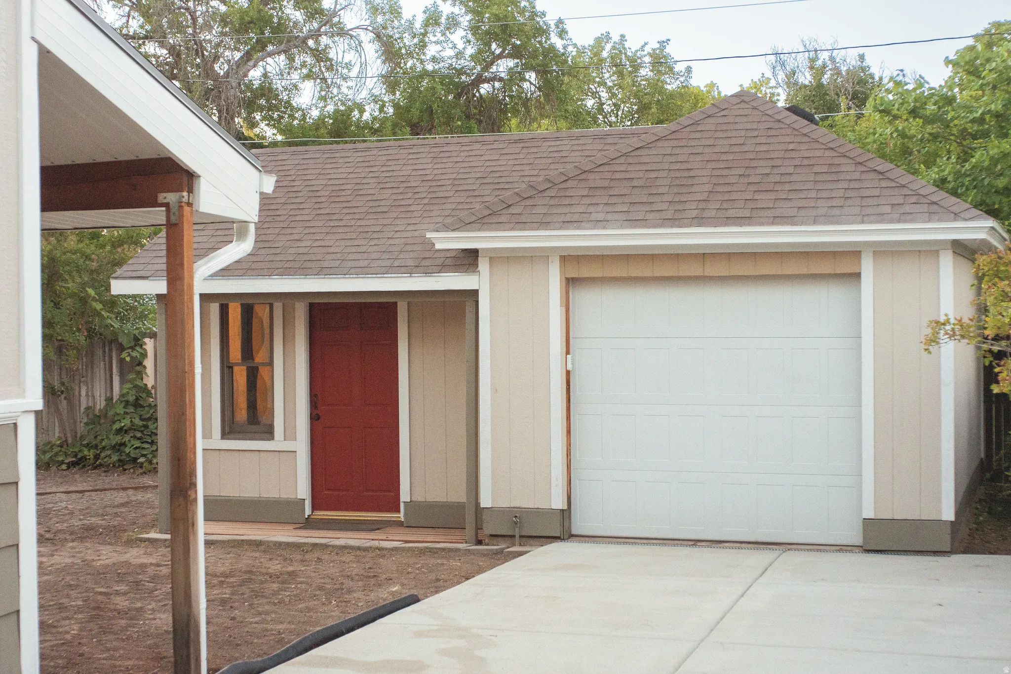 Attached garage with a panel door, concrete driveway, and covered entry with a red door