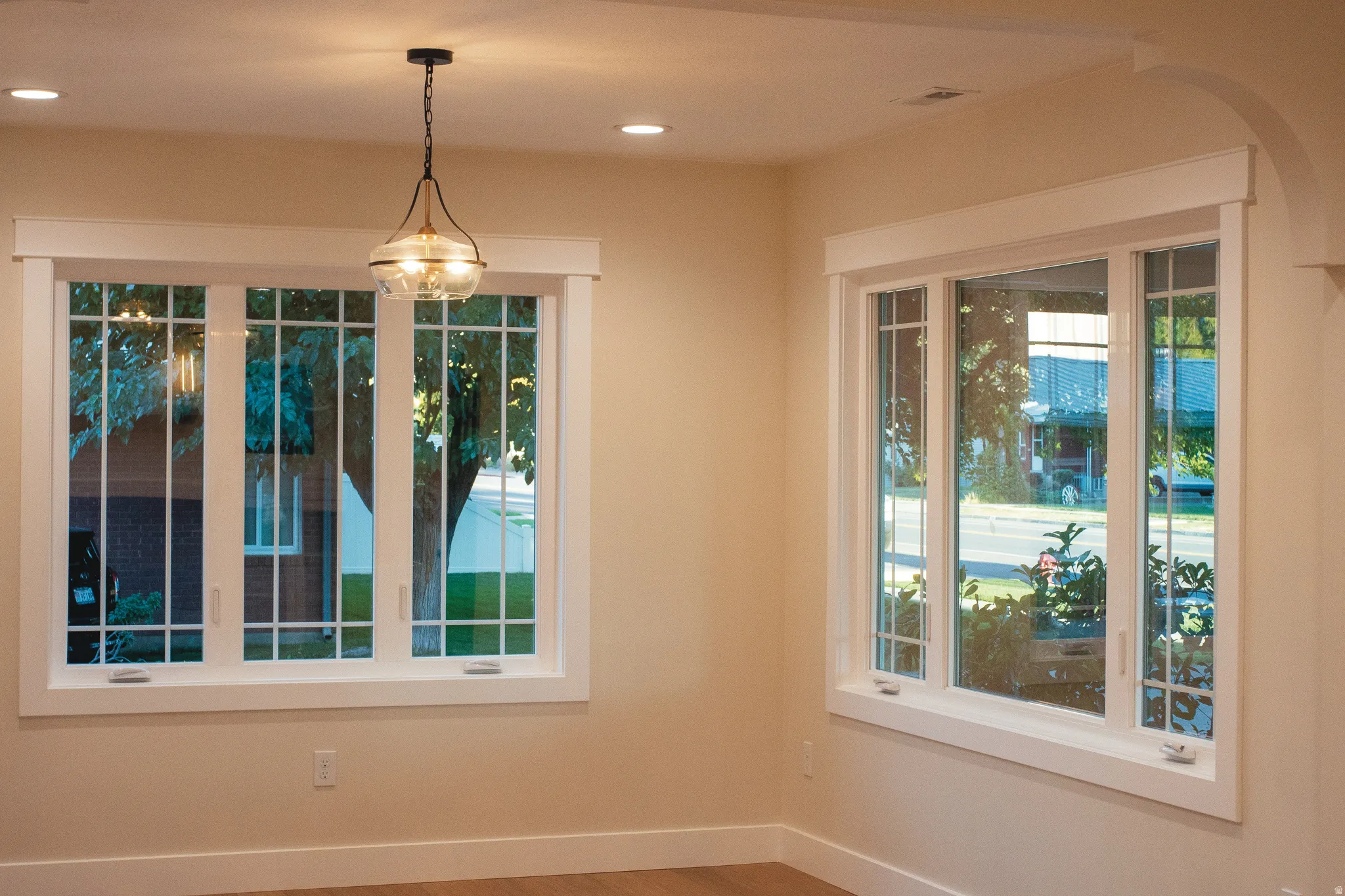 Recessed ceiling lighting, decorative pendant light fixture, multiple windows with grilles, wide window trim, arched doorway