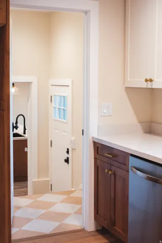 Kitchen area featuring white upper cabinetry, rich wood-finish lower cabinetry, light-toned countertop, and a stainless steel appliance