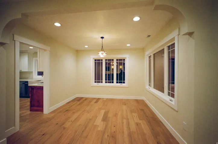Wood-finish flooring, recessed lighting, arched doorway, decorative pendant light, and multiple windows