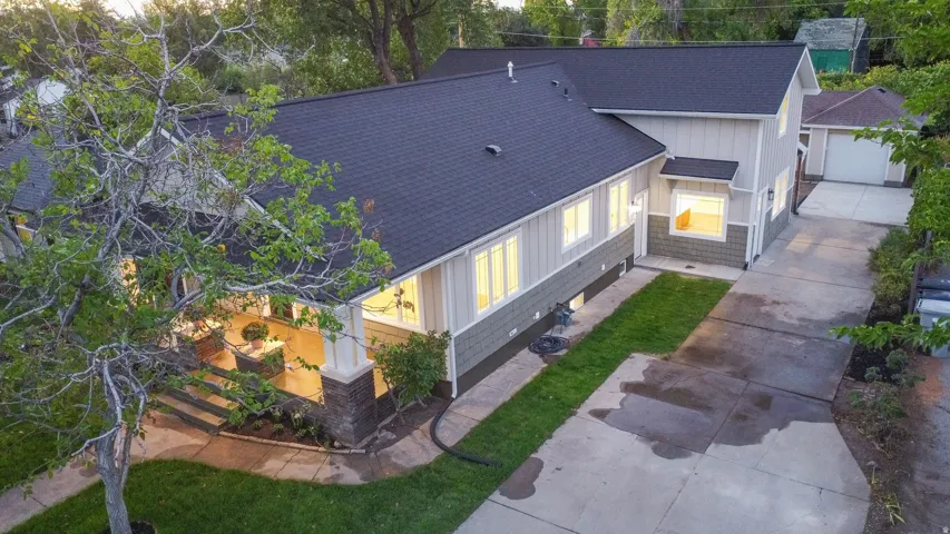 Asphalt shingle roof, light-colored siding, dark gray shake siding, front porch with stone-clad columns, concrete driveway, detached garage
