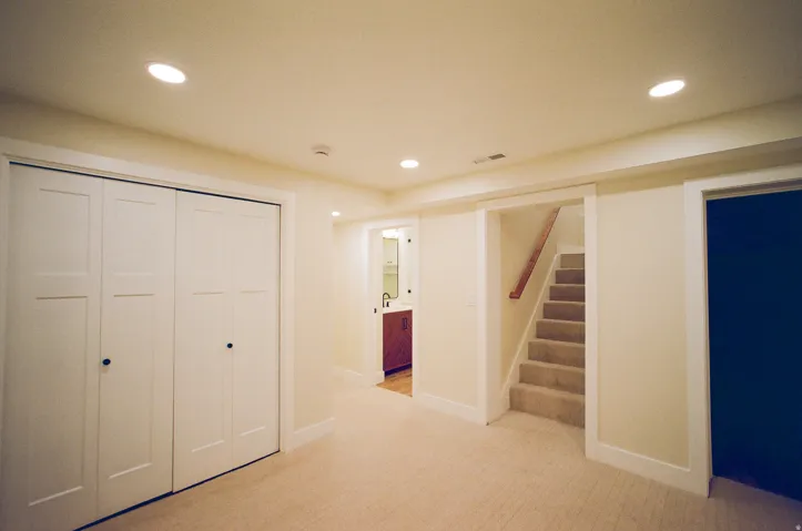 Recessed ceiling lighting, carpeted flooring, white paneled bifold closet doors, wood handrail, and white trim