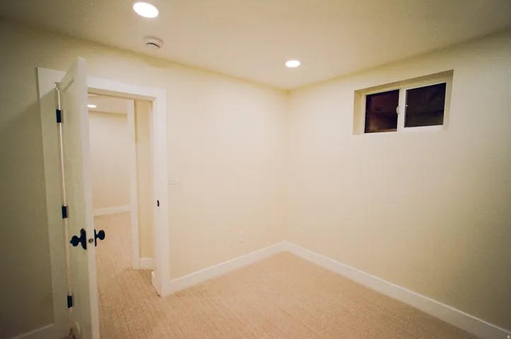 Recessed lighting, light-toned carpeting, white trim, and a window for natural light