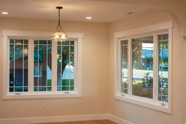 Recessed ceiling lighting, decorative pendant light fixture, multiple windows with grilles, wide window trim, arched doorway