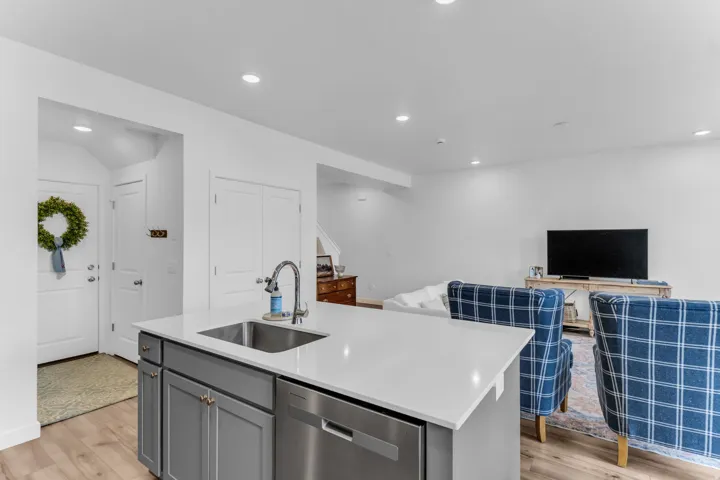 Kitchen island with an undermount sink, a stainless steel dishwasher, and quartz countertops