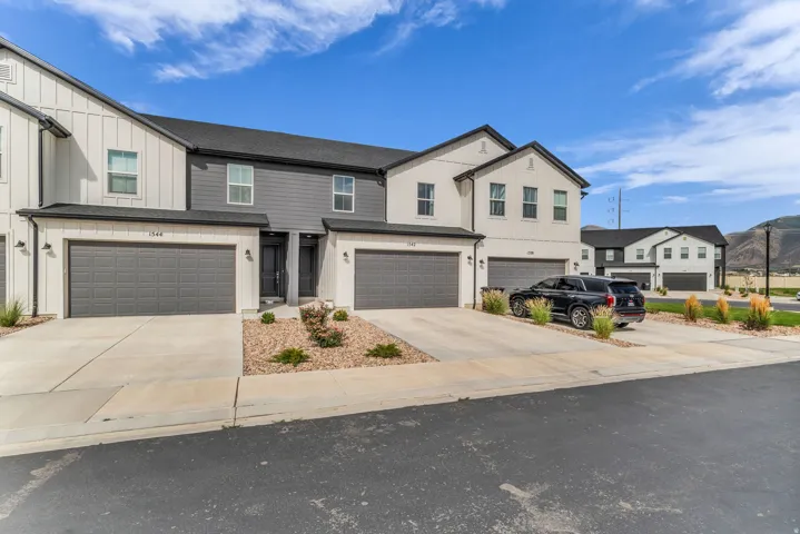 Modern townhome exterior with mixed siding, two-car garage, and concrete driveway