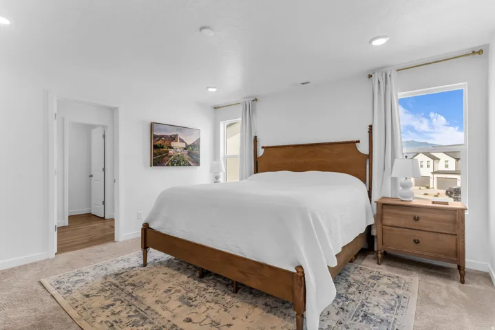 Recessed lighting, light-toned carpeting, and a window with a curtain rod