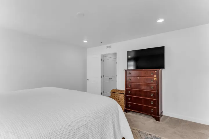 Recessed ceiling lighting, white walls, and a built-in closet with white bifold doors