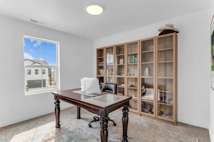 White walls with a large window, recessed lighting, and built-in shelving with glass-front doors