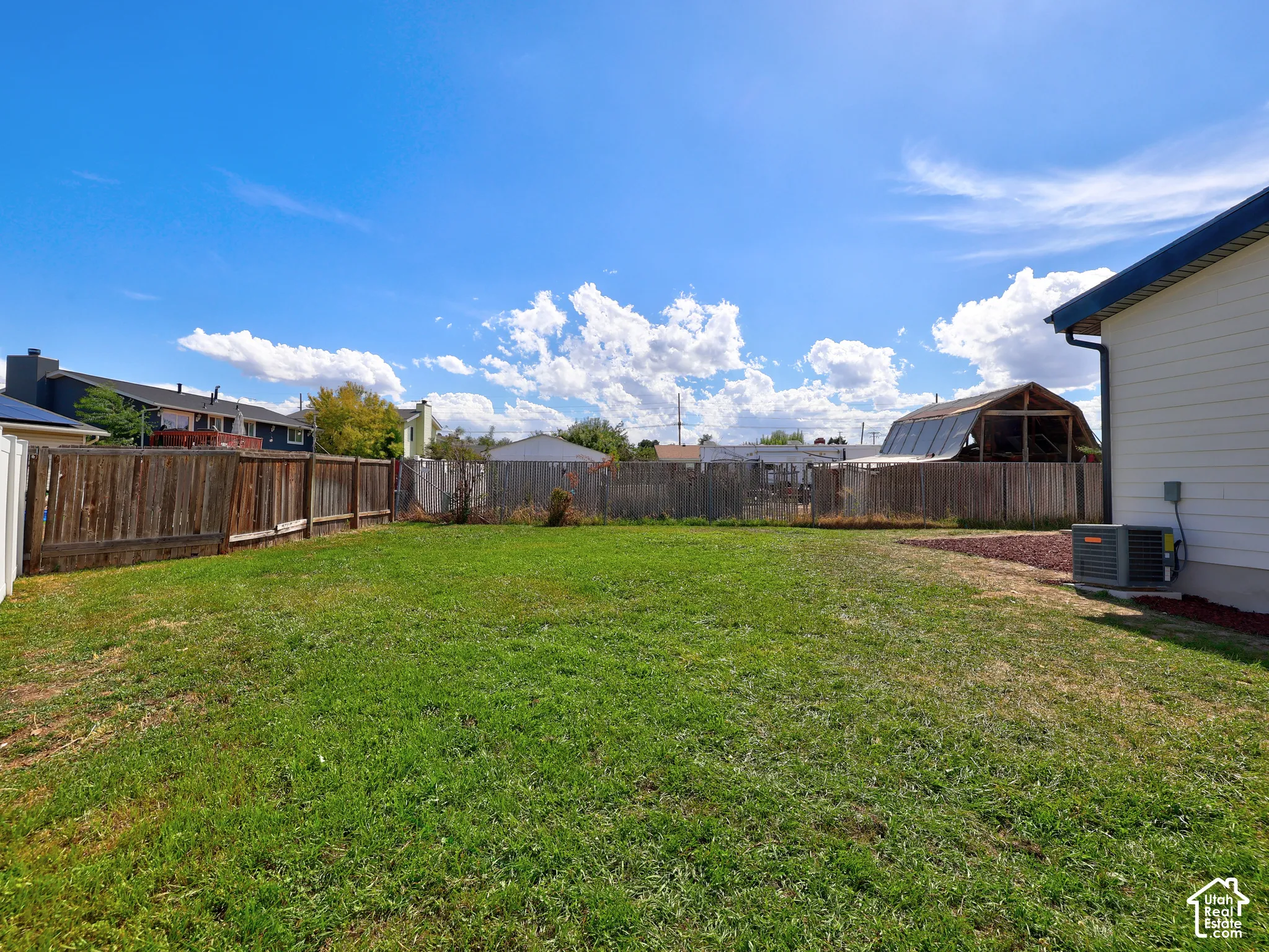 Expansive grassy backyard featuring a wood fence perimeter
