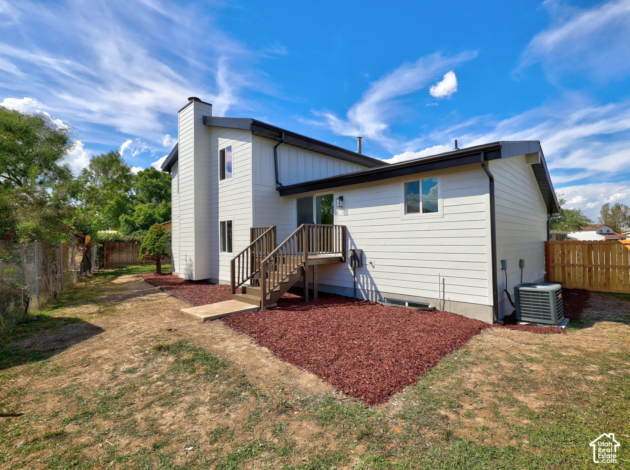 Exterior featuring white siding, dark trim, and a multi-level wooden deck with stairs