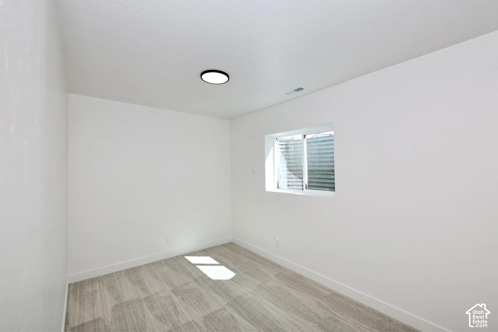 Recessed window, white painted walls, textured ceiling, flush-mount ceiling light, and carpeted flooring