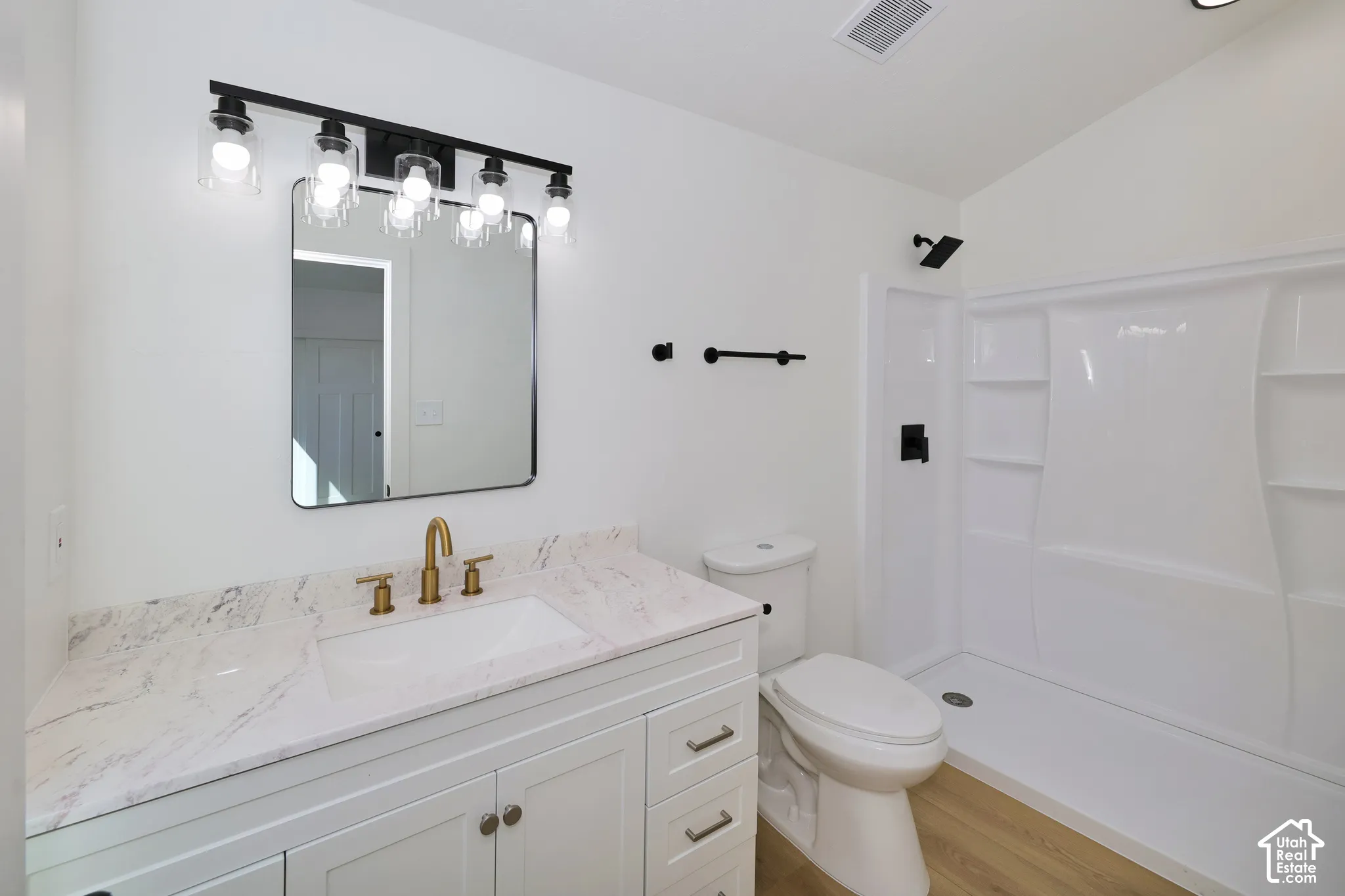 Bathroom featuring a white vanity with a stone countertop, a rectangular undermount sink, and a gold-finish faucet
