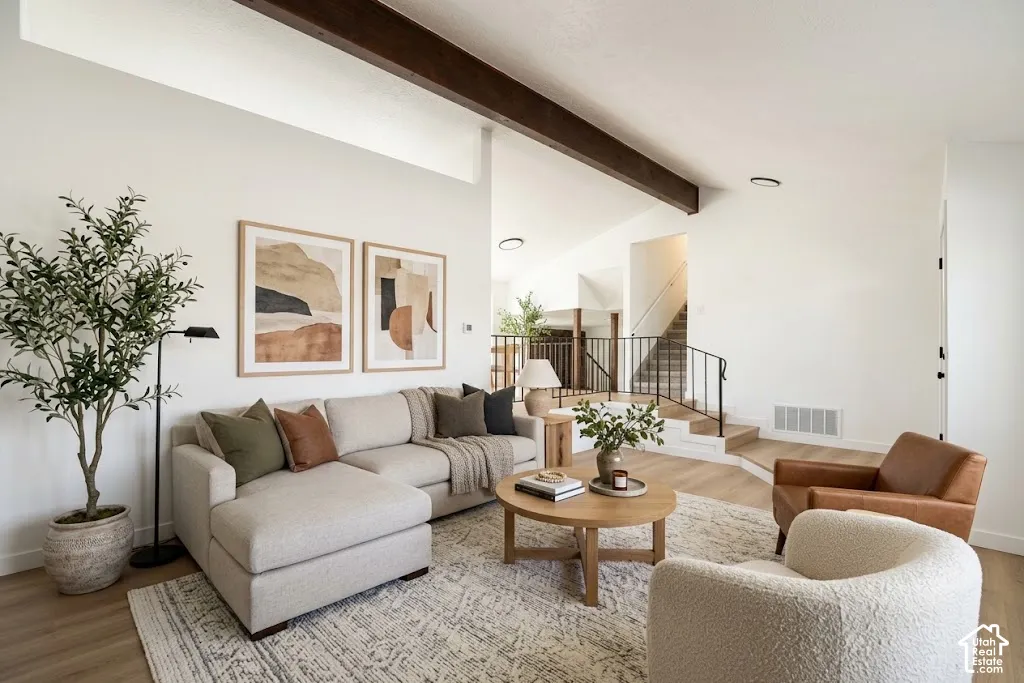 Vaulted ceiling with exposed wood beams, wood-finish flooring, recessed lighting, and a staircase with an iron railing
