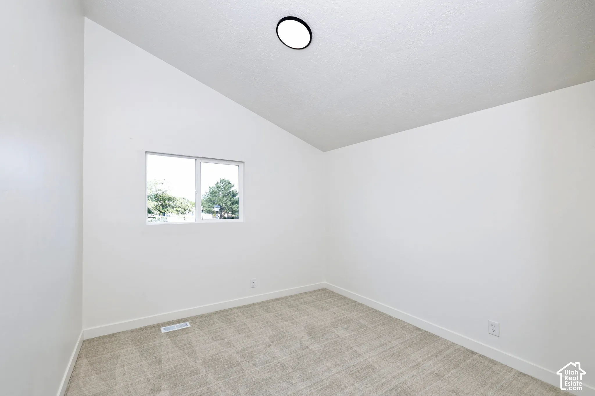Vaulted ceiling, white walls, light-toned carpeting, dual-pane window, flush-mount ceiling light