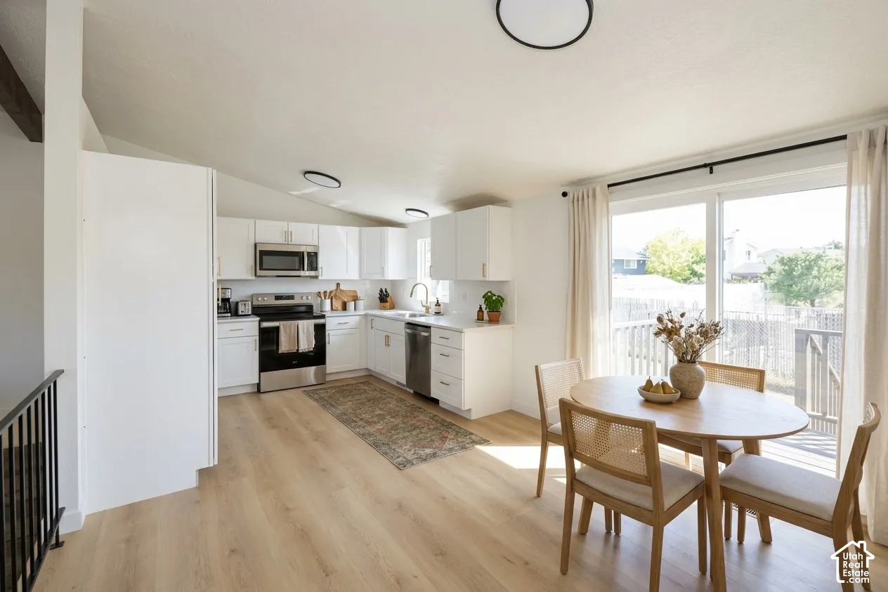 Kitchen featuring white cabinetry, stainless steel appliances, and light wood-finish flooring