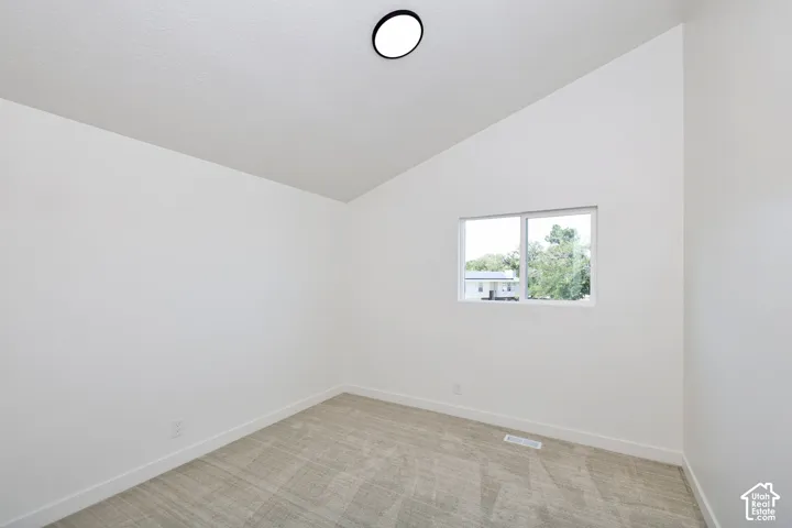 Vaulted ceiling, recessed lighting, double-pane window, and neutral carpeting