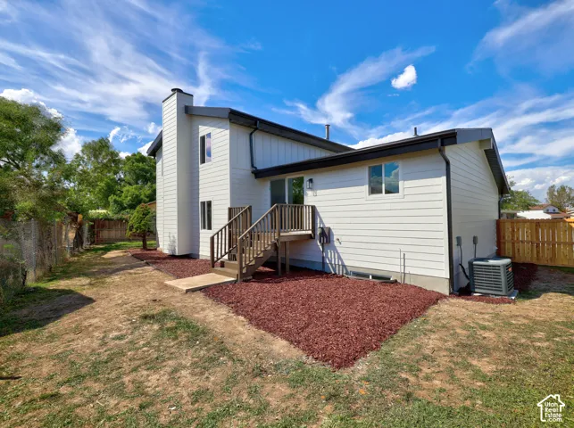 Exterior featuring white siding, dark trim, and a multi-level wooden deck with stairs