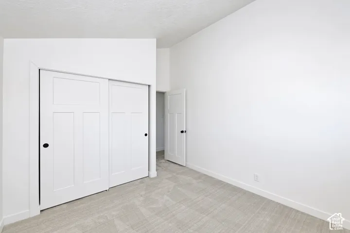 White paneled sliding closet doors, black hardware, neutral carpeting, white trim, and white walls