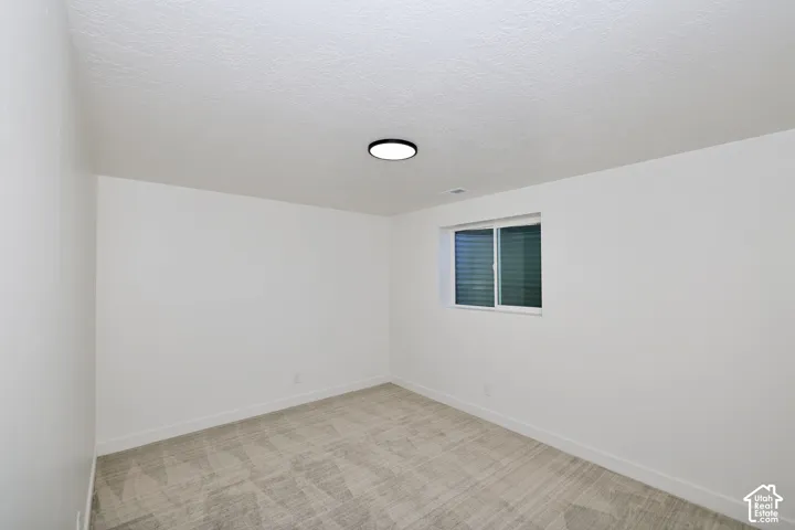 Carpeted flooring, white walls, and a single window with blinds