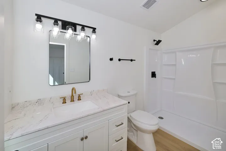 Bathroom featuring a white vanity with a stone countertop, a rectangular undermount sink, and a gold-finish faucet