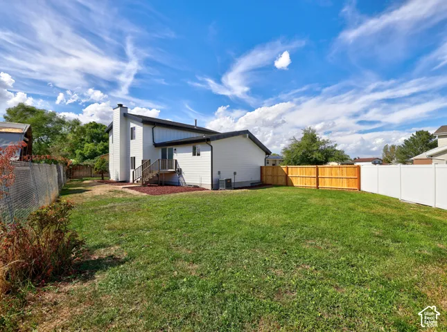Expansive yard with mature landscaping, a wooden deck, and a combination of chain link, natural wood, and white privacy fencing