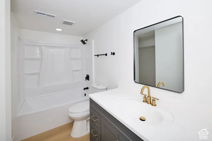 Bathroom featuring a tub/shower combination, dark gray vanity with a white countertop, gold-finish faucet, and a wall-mounted rectangular mirror