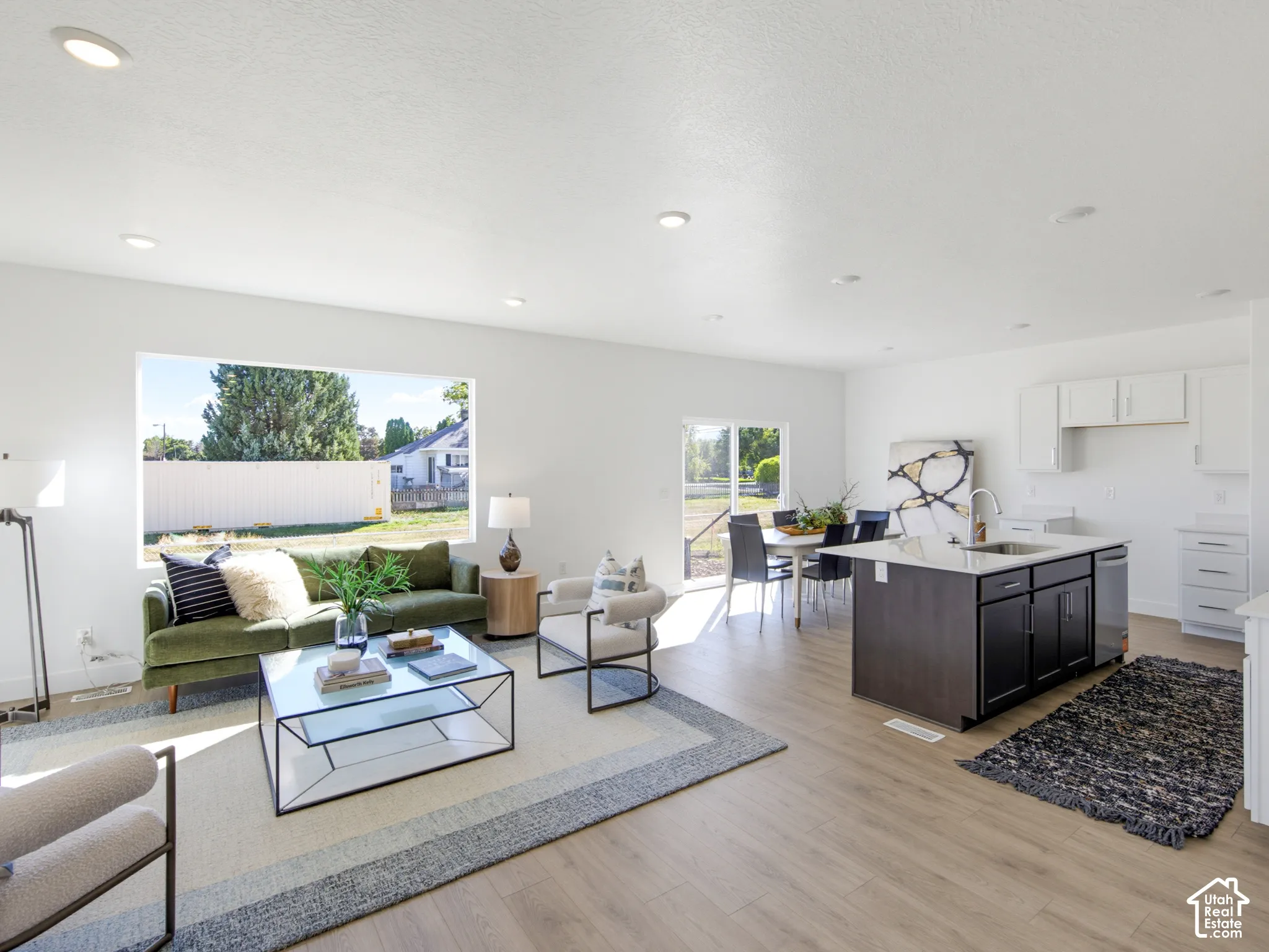 Open-concept interior featuring wood-finish flooring, recessed lighting, a kitchen island with stone countertops, and large picture windows
