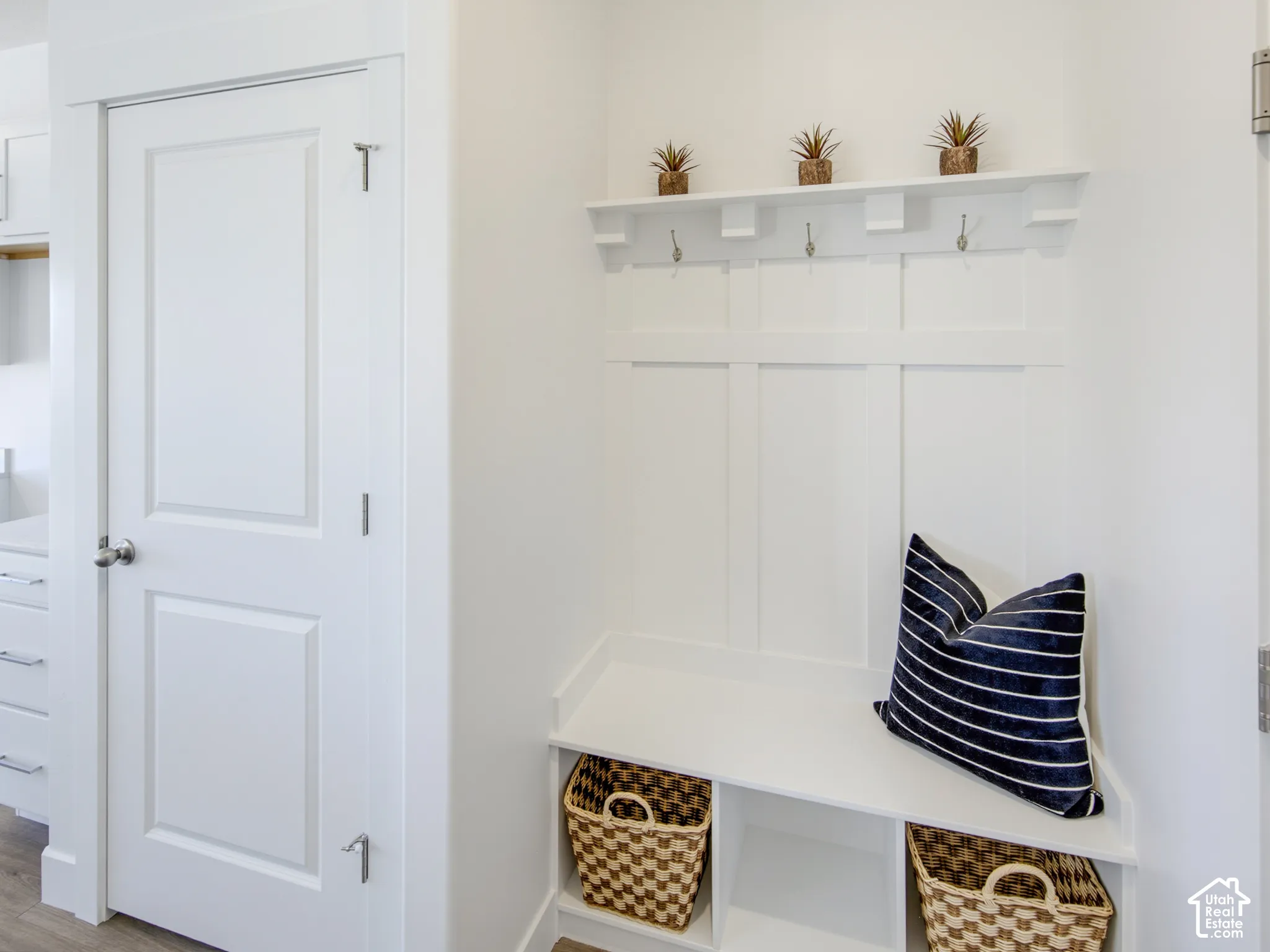 Built-in wall paneling featuring decorative hooks and a top display shelf, paired with a multi-compartment bench seat