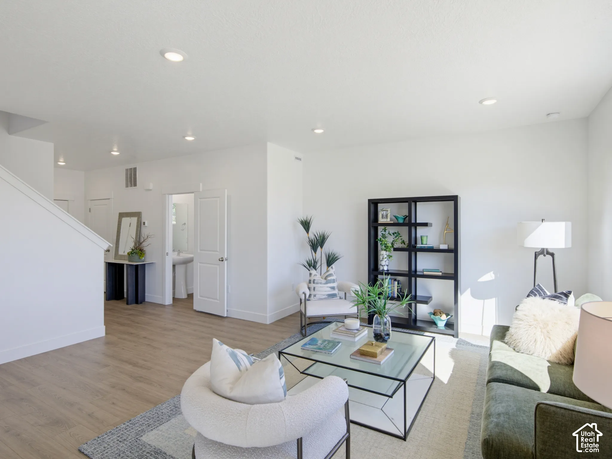 Neutral-toned living space featuring recessed lighting, wood-finish flooring, and a white pedestal sink