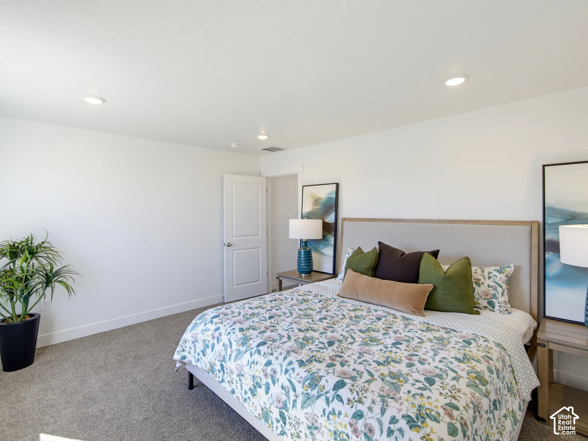Neutral wall-to-wall carpeting, recessed ceiling lighting, and a solid-core interior door with a brushed metal handle