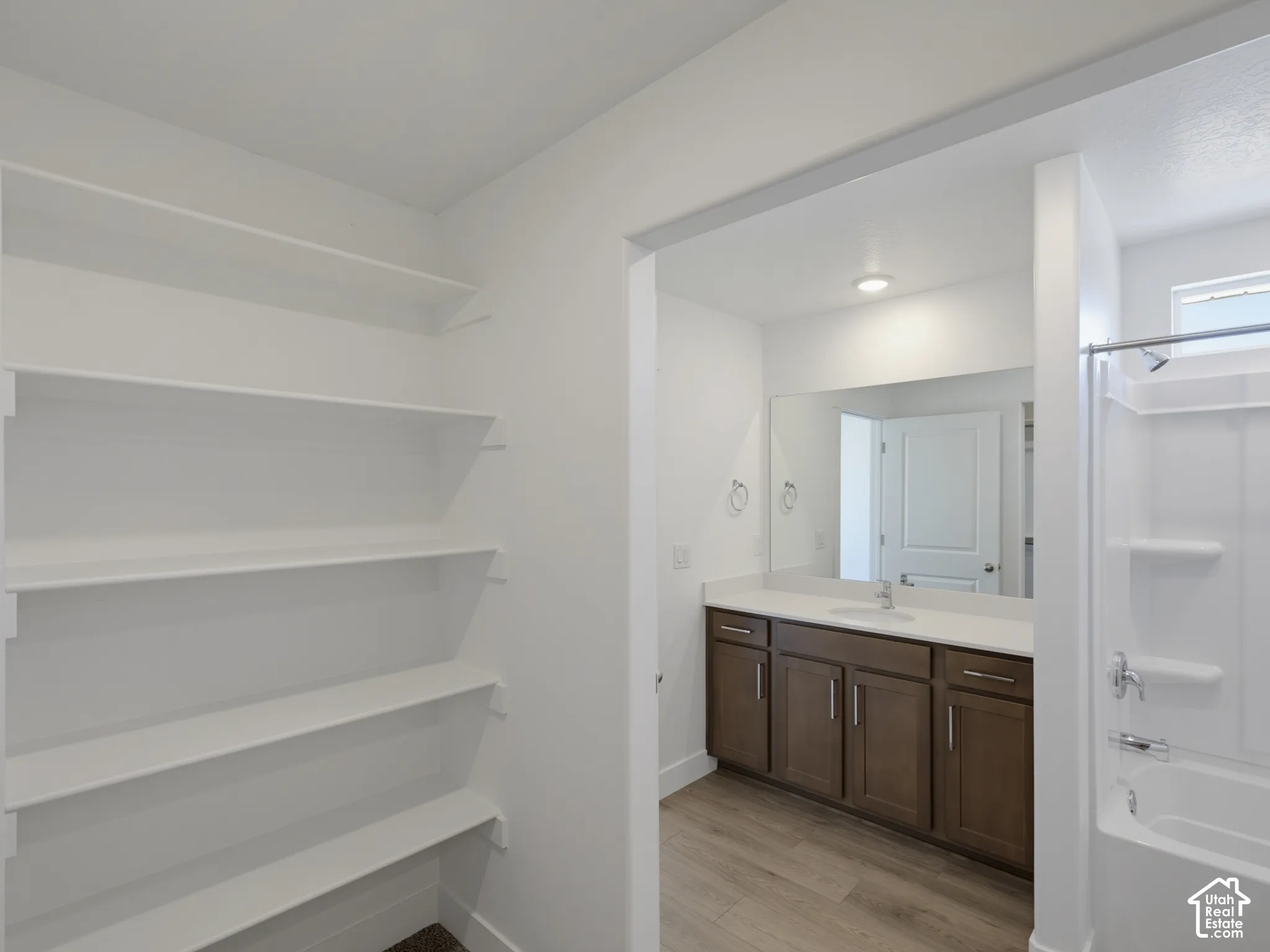 Built-in shelving, vanity with ample storage, integrated sink, large mirror, and shower-over-tub combination