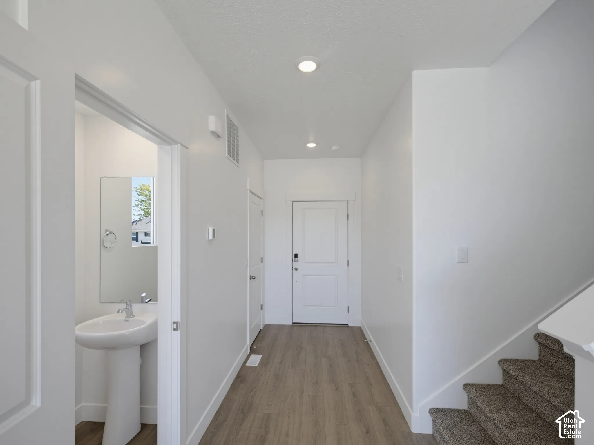 Entryway featuring wood-finish flooring, recessed lighting, white panel doors, and a carpeted staircase
