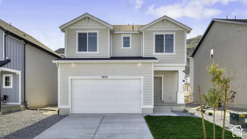 Two-story exterior featuring horizontal siding, dual gabled rooflines, an attached two-car garage, and a covered front entryway with a decorative pillar
