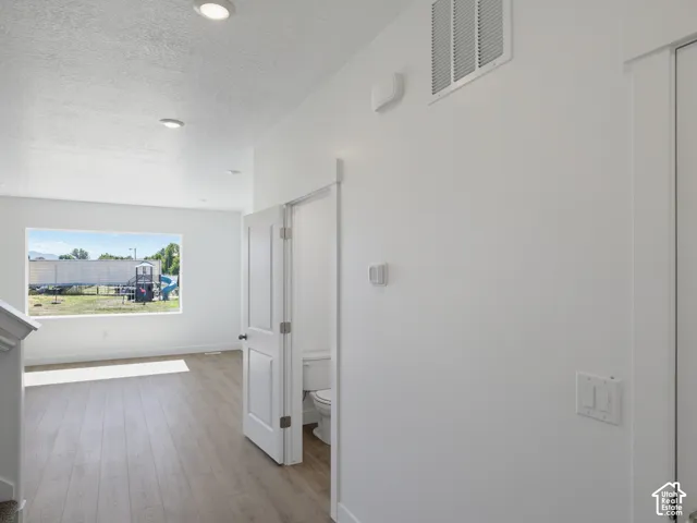 Recessed ceiling lighting, wood-finish flooring, white painted walls, and a white interior door