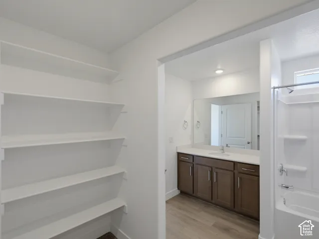 Built-in shelving, vanity with ample storage, integrated sink, large mirror, and shower-over-tub combination