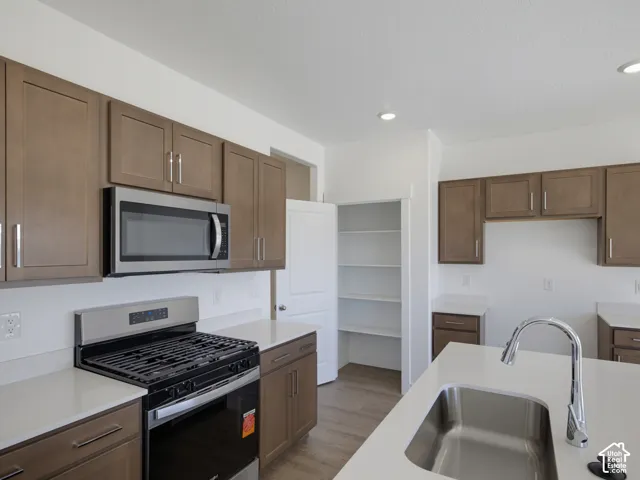Kitchen featuring stainless steel appliances, light wood-finish cabinetry, white countertops, a gas range, and recessed lighting